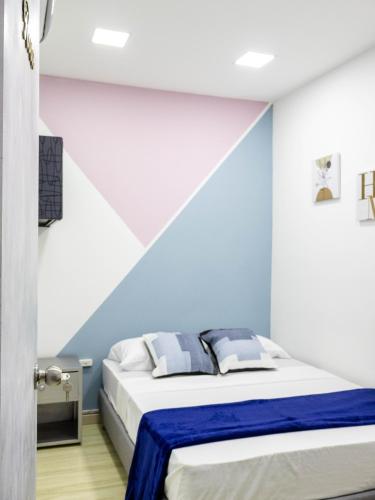 a bedroom with a bed with blue and white walls at S23 I City Lodge in Sabaneta