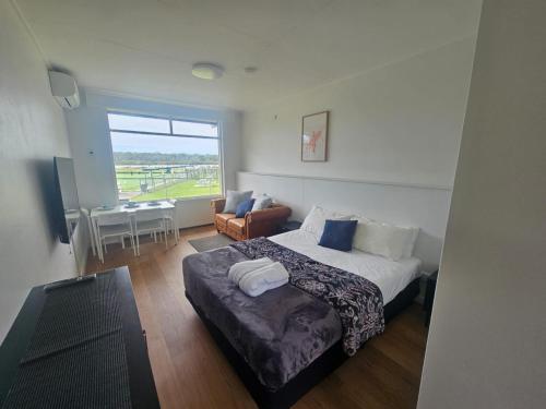 a bedroom with a bed and a table and a window at Waterview Motel Sussex Inlet in Sussex inlet