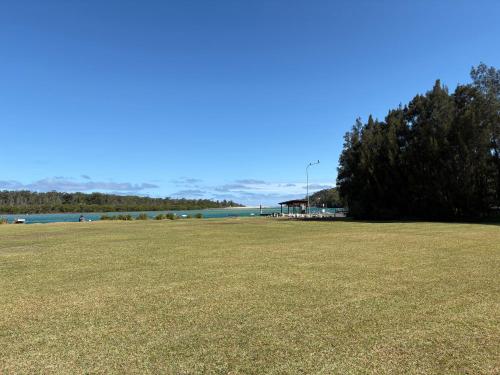 a large grass field with a tree and a lake at Waterview Motel Sussex Inlet in Sussex inlet