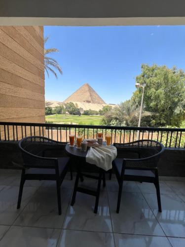 a table and chairs with a view of the pyramids at Glamour Pyramids BoutiQue Hotel in Cairo