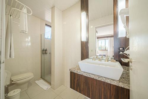 a white bathroom with a sink and a toilet at Hotel Prinz - PRZ000 in Joinville