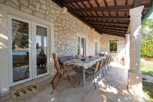 a patio with a table and chairs on a stone wall at Holiday Home Fiola in Zubovići