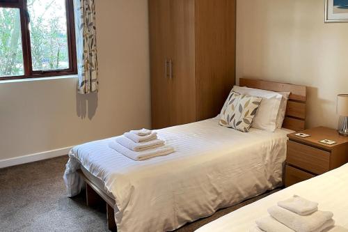 a bedroom with a bed with towels on it at Woodside Cottages - Beech cottage - Self-catering in Fletching