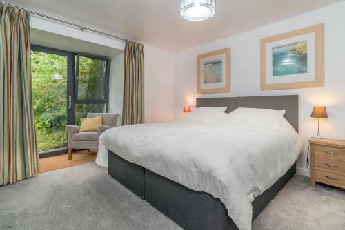 a bedroom with a bed and a chair and a window at Melin-Dwyfor in Criccieth