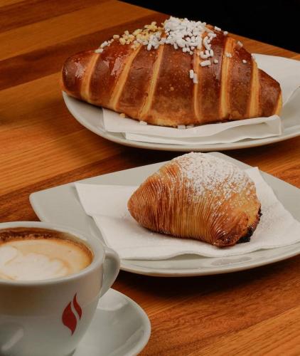 een tafel met twee borden brood en een kop koffie bij Kairos Relais in Napels