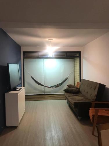 a living room with a couch and a television at Apartamento estiloso in Ubatuba