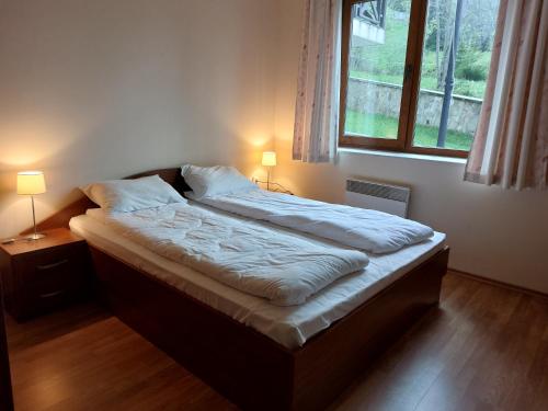ein Bett in einem Schlafzimmer mit zwei Lampen und einem Fenster in der Unterkunft Апартамент в Лъки Пампорово комплекс in Pamporowo