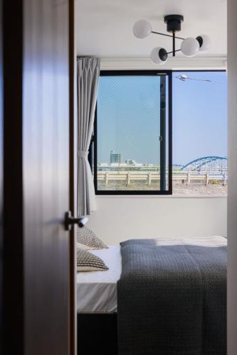 东京Skytree View Riverside Terrace的一间卧室设有一张床和一个享有海滩美景的窗户。