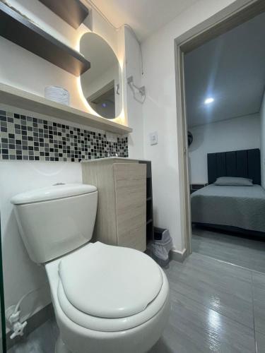 a bathroom with a white toilet and a bed at Hotel boutique Olaya 54 in Medellín