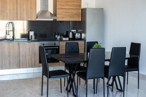 Una cocina con una mesa negra y sillas negras. en Birzebbuga Sunset, en Birżebbuġa