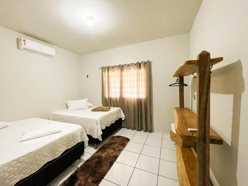 une petite chambre avec deux lits et une fenêtre dans l'établissement Pousada da Ana Maria, à Nobres