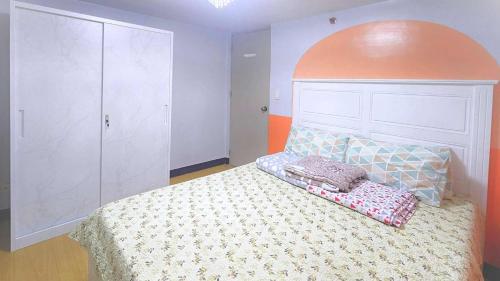 a bedroom with a bed with an orange headboard at Bright & Airy Loft Cambridge Village Charm in Cainta