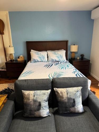 a bedroom with a bed and a couch with pillows at Stylish Studio Condo Near Magic Sands Beach in Kailua-Kona