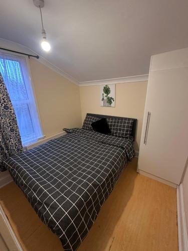 a bedroom with a bed with a checkered blanket at Double & Single rooms in Southall in Southall