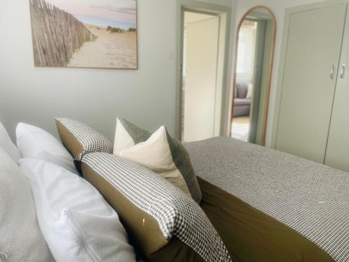 une chambre avec un lit avec des oreillers dessus dans l'établissement Beach Apartments at Flaxmill Bay Motel, à Cooks Beach