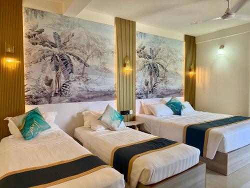 two beds in a room with a painting on the wall at Sorenzo Maldives in Thoddoo