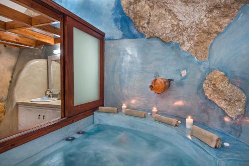 uma casa de banho com uma grande banheira num quarto com uma parede de pedra em Kokos Traditional Houses em Emporio