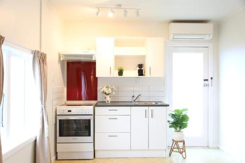 a kitchen with white cabinets and a sink at Skyline Urban - Entire Apartment with View, Netflix, Nespresso, and Street Parking in Wellington