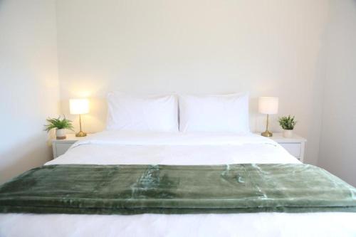 a bedroom with a white bed with two lamps at Skyline Urban - Entire Apartment with View, Netflix, Nespresso, and Street Parking in Wellington