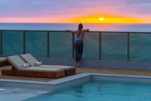 a woman standing on the edge of a swimming pool at Sais Beach Living Hotel in Maceió