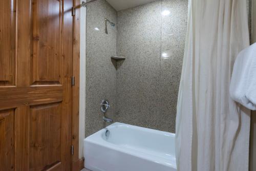 a bathroom with a tub and a shower with a white shower curtain at Zermatt Double Queen Suite Near Park City - 3074 in Mound City