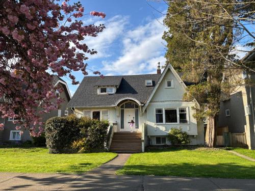 een wit huis met een meisje dat op de voordeur staat bij Bright Garden Suite Across From Park in Kitsilano in Vancouver