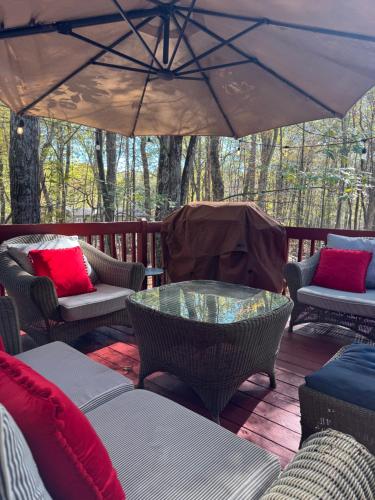a patio with chairs and an umbrella on a deck at Poconos Chalet -Kayaks- HotTub-Karaoke-Lake in East Stroudsburg