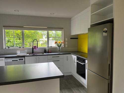a kitchen with white cabinets and a stainless steel refrigerator at Hamilton Greenhill Lodge - Private Pool & Easy Highway Access in Hamilton