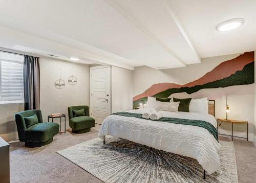 a bedroom with a large bed and two green chairs at Institute Den Downtown Modern Basement Suite in Colorado Springs