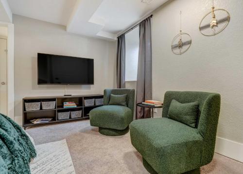 a living room with two chairs and a flat screen tv at Institute Den Downtown Modern Basement Suite in Colorado Springs