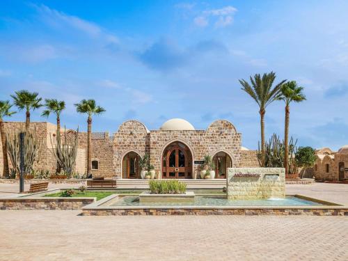 库塞尔Movenpick Resort El Quseir的一座前面有棕榈树的建筑