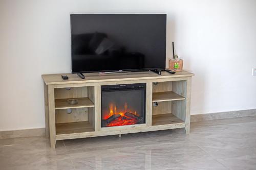 Un centro de entretenimiento de madera con chimenea y televisor encima. en Birzebbuga Sunset, en Birżebbuġa