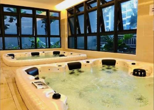 una bañera de hidromasaje en una habitación con ventanas en Cozy Stay Pool Atlantis Residence, en Melaka