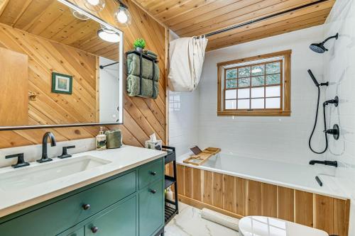 a bathroom with a tub and a sink at 8 Mi to Mt Snow Cozy Bear Cabin with Hot Tub! in Wilmington