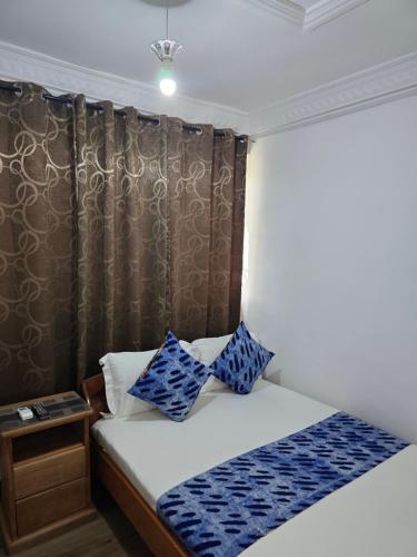 a bedroom with a bed with blue pillows on it at Cape Coast Travellers' Inn in Cape Coast