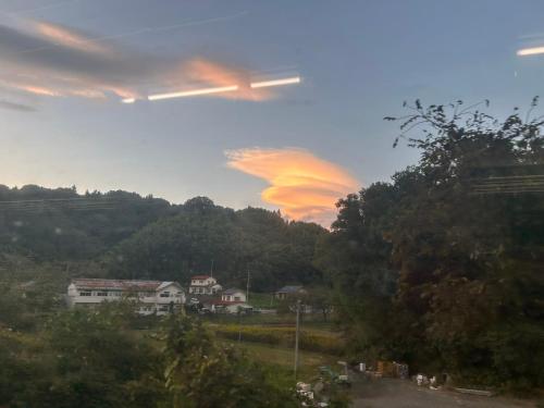 un avion volant dans le ciel avec un coucher de soleil dans l'établissement 民宿とまとハウスTomato House, à Funehiki