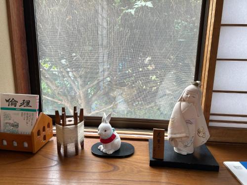 un rebord de fenêtre avec des figurines sur une table à côté d'une fenêtre dans l'établissement 民宿とまとハウスTomato House, à Funehiki