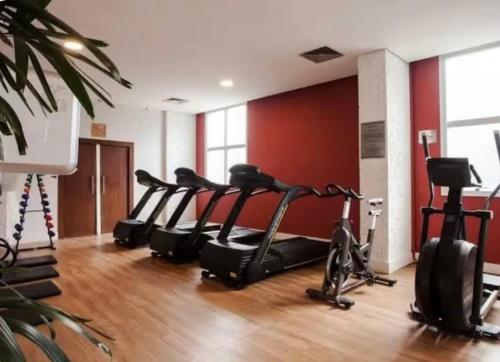 een fitnessruimte met verschillende loopbanden en een rij hometrainers bij Flat no hotel Comfort em Alphaville in Barueri