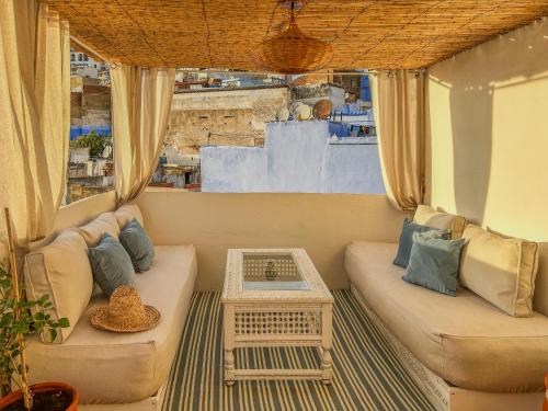 a living room with a couch and a table at Chambre Lumineuse avec Vue Ruelle Bleue et Terrasse in Chefchaouene