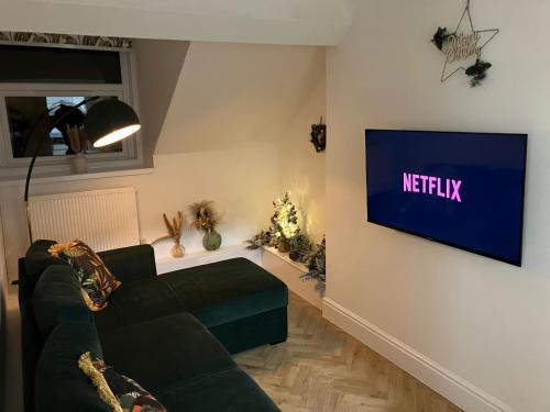 a living room with a couch and a tv on a wall at Seashell Apartment in Barmouth