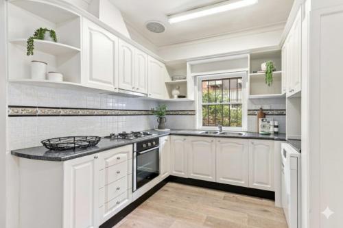 Una cocina blanca con gabinetes blancos y un fregadero. en Home in Leichhardt, Sydney, en Sídney