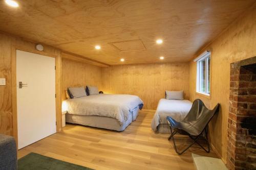 a room with two beds and a chair in it at Mataura River Hideaway in Ardlussa