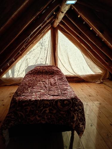 a bed in a tent with a wooden floor at Cabañas Don Fernando in Santa Rosa de Calamuchita
