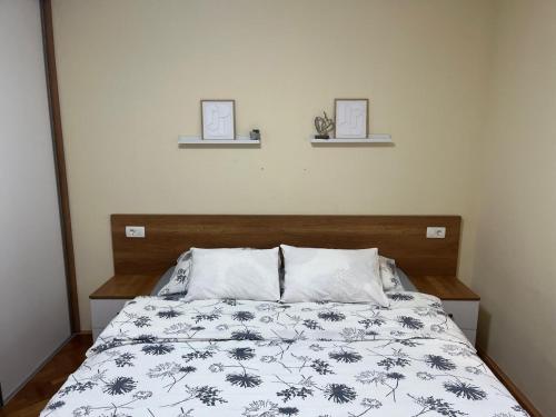 a bed with a black and white comforter and two pictures at Apartment Lara in Mostar