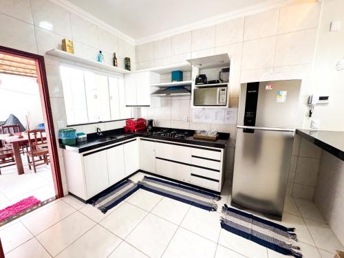a kitchen with white cabinets and a stainless steel refrigerator at Casa victória Régia in Camocim