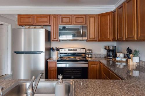 约翰逊城Spacious 3 Bed Condo Near ETSU的厨房配有木制橱柜和不锈钢冰箱