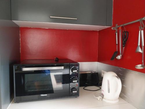Un horno microondas en una cocina con paredes rojas. en Manuia Lodge, en Punaauia