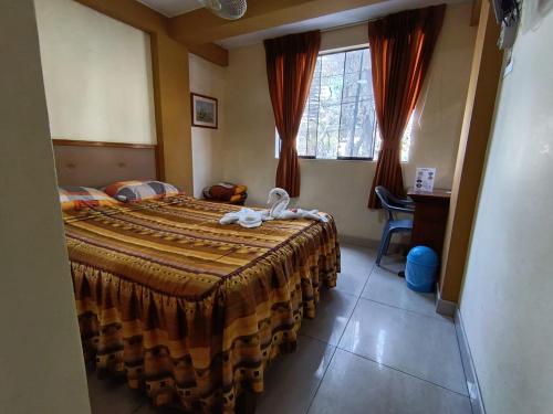 ein Schlafzimmer mit Bett, Schreibtisch und Fenster in der Unterkunft Hostal Winya in Lima