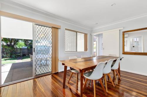 a dining room with a wooden table and white chairs at Nonna and Pops in Mylestom