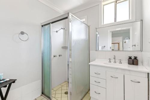 a white bathroom with a shower and a sink at Nonna and Pops in Mylestom